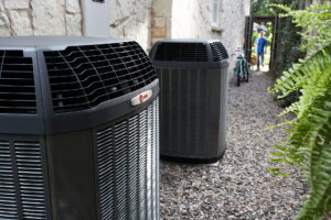 Two outdoor heat pump units beside a stone house, suitable for heat pump maintenance or repair.