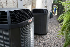 Two outdoor heat pump units beside a stone house, suitable for heat pump maintenance or repair.